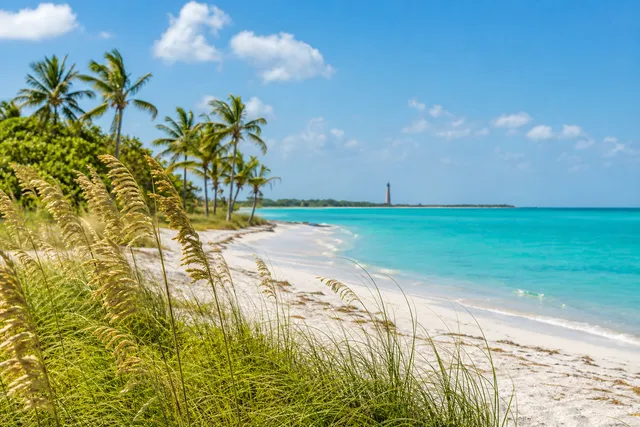 Sanibel Island beach with sea oats, lighthouse, and turquoise water